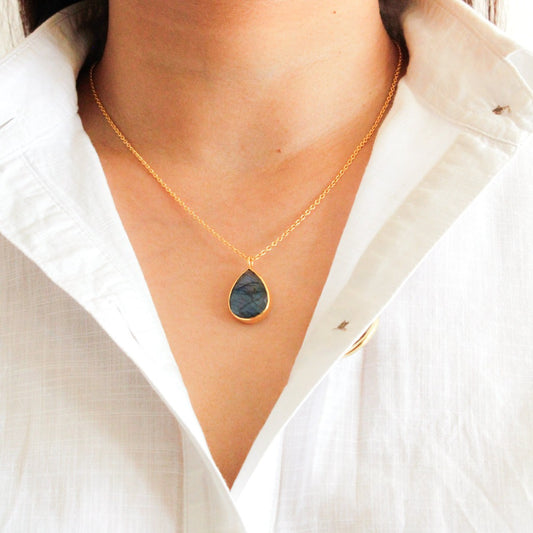 Women in a white summer shirt wearing Amara pear-shapped Labradorite necklace from Somya London